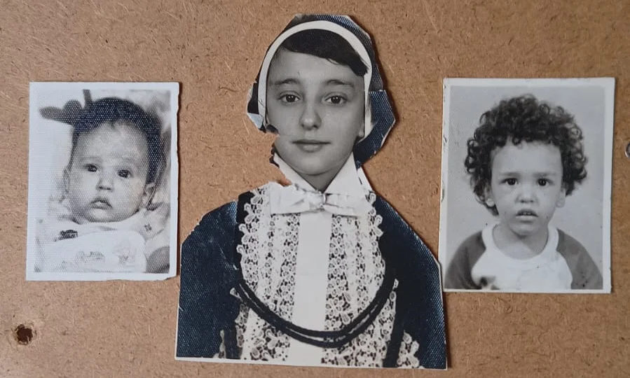 Três fotos antigas em preto e branco afixadas em painel de cortiça: ao centro, recorte de criança com traje tradicional, touca e laço rendados; à esquerda, bebê; à direita, criança com cabelos cacheados.